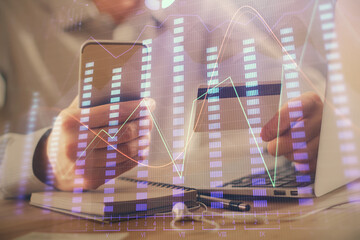 Double exposure of man hands holding a credit card and Forex graph drawing. Stock trading and digital fintech in Internet E-commerce concept.