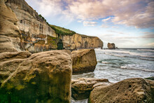 Sitting On A Large Boulder Under The Steep Cliff  At Tunnel Beach Coastline Watching The World Go By