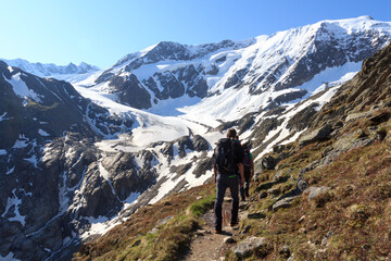 group of people hiking towards glacier taschachferner and mountain snow panorama with blue sky in ty