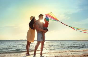 Poster - Happy parents and their child playing with kite on beach near sea. Spending time in nature