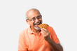 Asian Indian old man or senior adult eating sweet belgian waffle