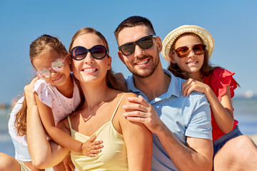 Poster - family, leisure and people concept - happy mother, father and two daughters on summer beach