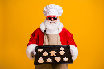 Poster - Photo of santa claus chef grandpa grey beard hold ready ginger bread healthy sweets cool grandparent take care kids wear costume gloves sun specs cap apron isolated yellow color background