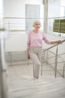 © zinkevych - Grey-haired woman in casual clothes going upstairs