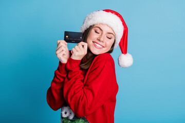 Poster - Photo portrait of glad woman holding credit card in two fingers hands eyes closed isolated on pastel light blue colored background