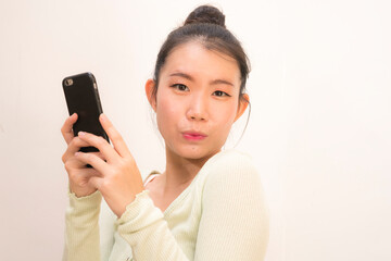 Poster - young attractive and sweet Asian Chinese woman posing happy and cheerful using internet mobile phone isolated on studio background in communication concept