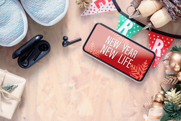 Poster - New Year New Life resolutions fitness healthy goals concept. New Year New Life text on mobile phone on table with sport shoes, wireless earphone,  and Christmas ornaments. Mock up smartphone