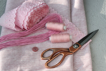 Natural fabric, thread, lace and tailor's scissors. A set for sewing clothes.
