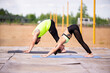 © Georgii - Pilates or yoga workout of young couple in stylish sportswear outdoor on sports mats, wellness in urban