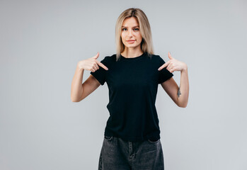 Wall Mural - Stylish blonde girl wearing black t-shirt posing in studio