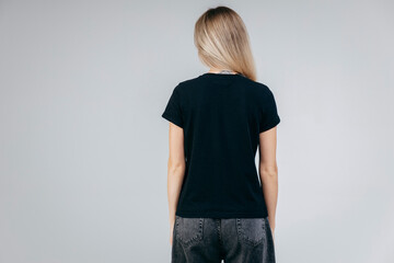 Wall Mural - Back of stylish blonde girl wearing black t-shirt posing in studio