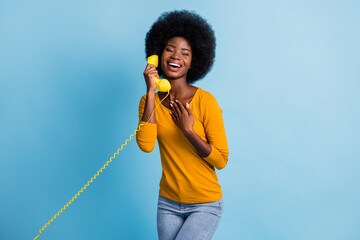 Poster - Photo portrait of black skinned woman talking on retro telephone keeping handset with wire laughing isolated on bright blue color background