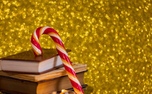 Christmas Composition. Striped Candy Cane And Books On A Gold Background. Copy Space. New Year.