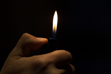 male hand holding a lighter with a large flame on a black background