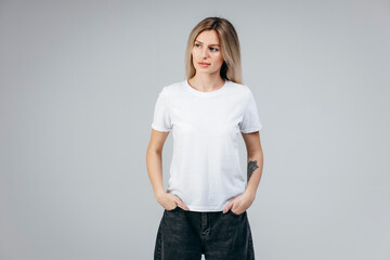 Wall Mural - Stylish blonde girl wearing white t-shirt posing in studio