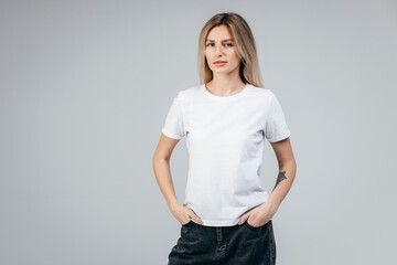 Wall Mural - Stylish blonde girl wearing white t-shirt posing in studio