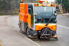 A Hydraulically Powered Road Sweeper Sweeps The Street.