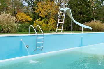 backyard swimming pool with pool slide and ladder emptied out shutting down for winter