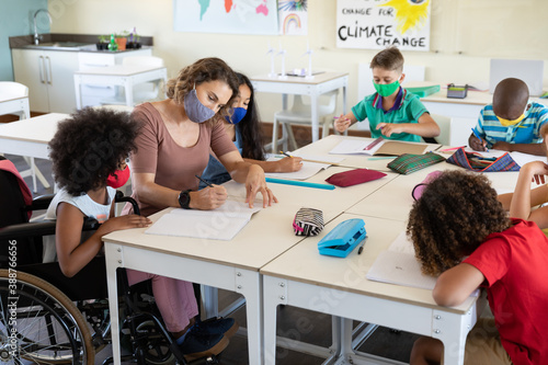 Fotografía Female teacher wearing face mask teaching a disable girl in class