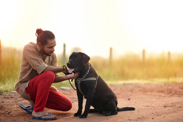 Young Indian Man playing with Labrador Dog in ground & Looking at his Dog