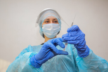 young woman doctor nurse in a protective mask with a syringe in her hand