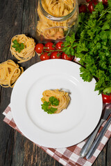 Wall Mural - table setting with white plate, pasta and vegetables on a wooden table, vertical