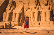 © unai - A young tourist in red dress walking towards the Abu Simbel Temple in southern Egypt in Nubia next to Lake Nasser. Temple of Pharaoh Ramses II