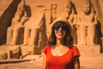 a young tourist in a red dress smiling at the abu simbel temple in southern egypt in nubia next to l