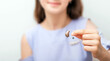 © Peakstock - Hearing aid in hand of a teenage girl patient, close-up. Selection of hearing aid for a child. Hearing concept