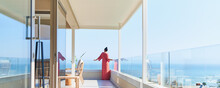 Woman In Long Dress Enjoying Sunny Scenic Ocean View On Luxury Balcony