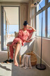 © Trevor Adeline/Caia Image - Woman relaxing and reading book in sunny window