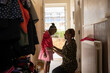 © Himalayan Pics/Caia Image - Mother helping daughter with jacket at front doorway