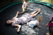 © Tom Merton/Caia Image - Daughters playing around carefree mother laying on trampoline