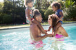 © Tom Merton/Caia Image - Playful parents playing chicken with daughters on shoulders in pool
