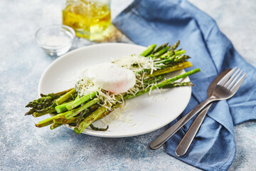 Wall Mural - Green asparagus with poached egg and parmesan, vegetarian breakfast served on white plate on light background.