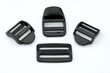 Black plastic buckles for a belt on a white background. Plastic straps of different widths for the straps of a bag and a backpack. Sewing accessories made of plastic.