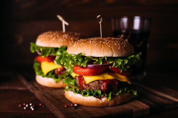 Two home made fresh tasty burgers with lettuce and cheese on wooden table.