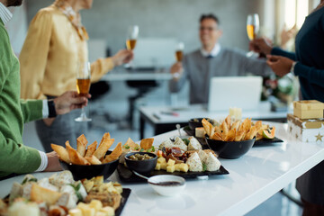 Variety of food on the table with business people in the background at office party