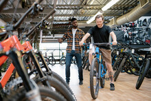 Male Bike Shop Owner Helping Customer Try Mountain Bike