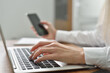 © pridannikov - Close up of young female hands typing on the keyboard and making a call on a smartphone