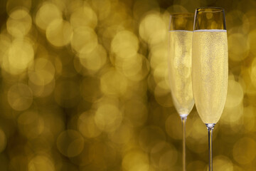 Two glasses of champagne on golden background, with copy space. champagne on golden stylish background with golden bokeh.