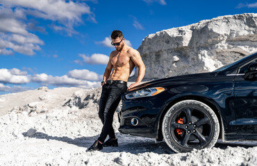 Wall Mural - Close up portrait of a young shirtless man standing near his car outside. White quarry background.