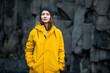 © Sergey Lukankin/Stocksy - Woman in a yellow jacket on a background of basalt rocks, Iceland