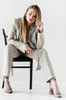 © LIGHTFIELD STUDIOS - trendy woman in suit sitting on chair and looking down on white