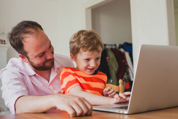 father teaching excited child to use laptop computer