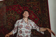 © Anna Artemenko/Stocksy - portrait of a young cheerful man on a carpet background