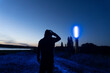 © Dave Wall/Stocksy - A hooded figure looking at a futuristic blue light at night