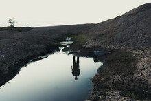 A Haunted Landscape Of A Ghostly Reflection Of A Figure In Water