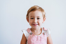 Smiling Baby Girl Standing Against White Wall