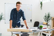 © Giorgio Fochesato/Westend61 - Smiling man leaning on desk while standing at office